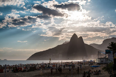 People on beach against sky during sunset