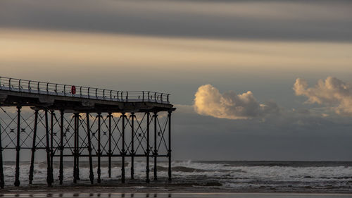 Pier over sea against sky during sunset