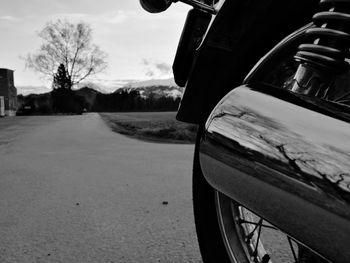 Close-up of wheel by road against sky