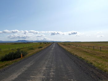 Road amidst field against sky