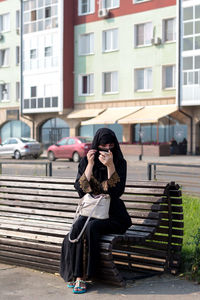 Young woman using mobile phone while sitting in park