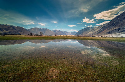 Scenic view of lake by mountains against sky