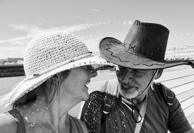 Cheerful mature couple wearing hat against sky