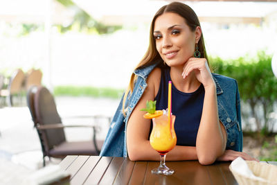Young woman with drink sitting at sidewalk cafe