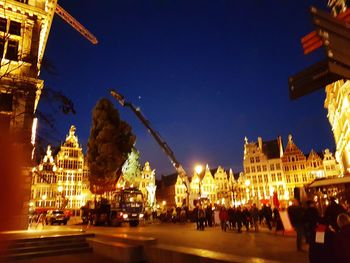 People in illuminated city against clear sky at night