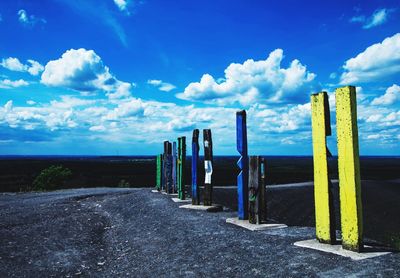 Wooden posts on landscape against blue sky