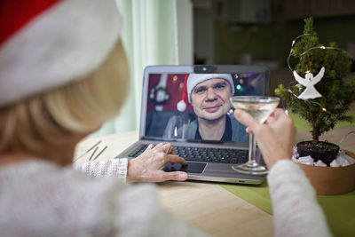 Safe online celebration. senior woman holding a glass of wine and celebrating christmas virtually 