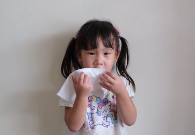 Portrait of cute girl drinking against wall