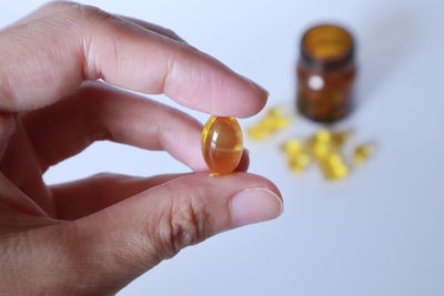 Close-up of hand holding colored pencils over white background