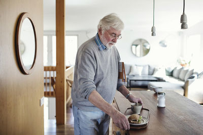 Senior man holding breakfast in tray at home