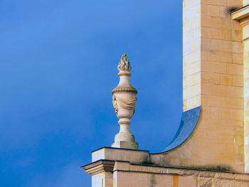 Low angle view of statue of building against blue sky