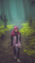 Portrait of young woman standing in forest