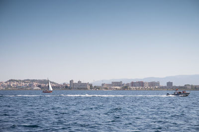 Sailboats sailing in sea against clear sky