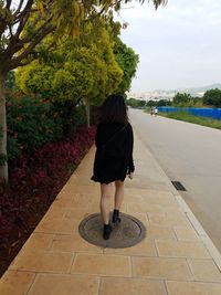 Rear view of woman riding bicycle on footpath