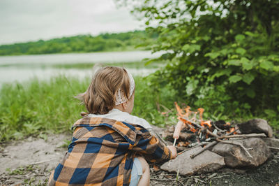 Rear view of woman on shore against trees