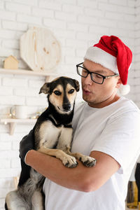 Midsection of man with dog wearing hat