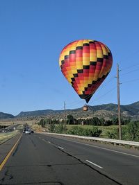 A hot air balloon drifts low over the road