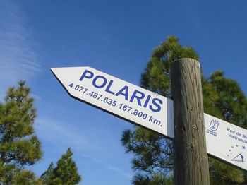 Low angle view of road sign against clear blue sky