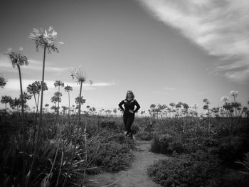 Woman walking on field against sky
