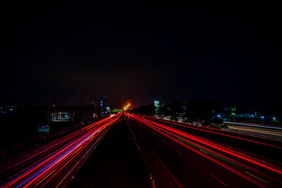 Light trails on road against sky at night