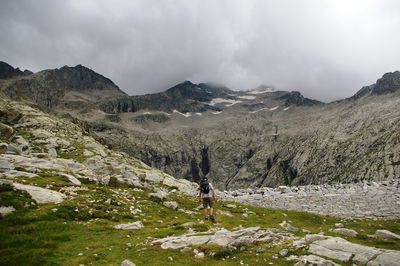 Man hiking on mountain against cloudy sky