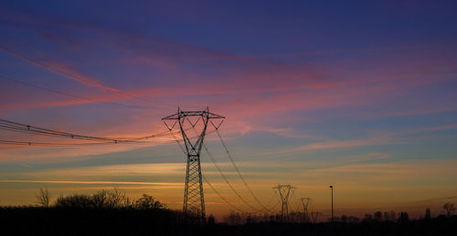 Low angle view of silhouette electricity pylon against romantic sky