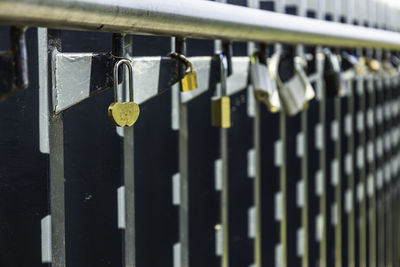 Heart-shaped padlock hanging on rails among other variegated padlocks