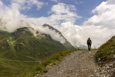 Rear view of man on mountain road against sky