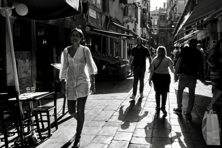 REAR VIEW OF PEOPLE WALKING ON STREET IN CITY