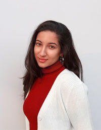 Portrait of young woman standing against wall