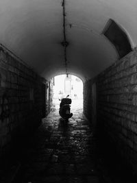 Rear view of man in tunnel against building