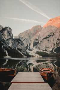 Boat moored on lake by mountains against sky