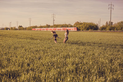 Friends enjoying on grassy field against sky