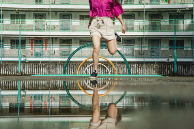 Low section of woman on railing against buildings in city