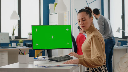 Side view of woman using laptop at office