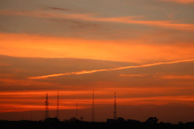 Silhouette electricity pylon against romantic sky at sunset