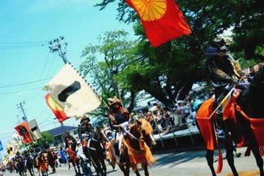 large group of people, men, flag, lifestyles, horse, person, leisure activity, celebration, animal themes, transportation, crowd, day, cultures, traditional festival, street, on the move, traditional clothing, mode of transport, tree