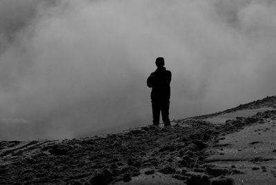 Rear view of silhouette man standing on land against sky