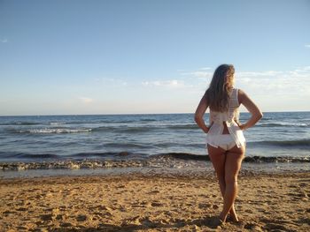 Rear view of young woman standing at beach