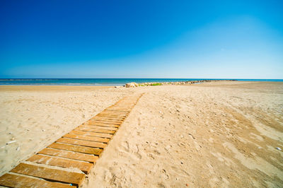 Scenic view of beach against clear blue sky