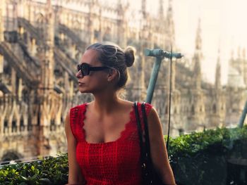 Woman wearing sunglasses while standing against building