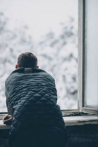 Rear view of people looking through window at home