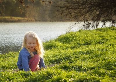 Cute girl crouching against lake
