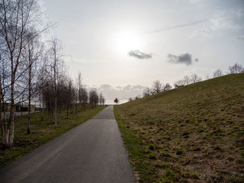 Road amidst bare trees against sky