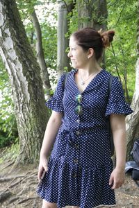 Young woman looking away while standing on tree trunk