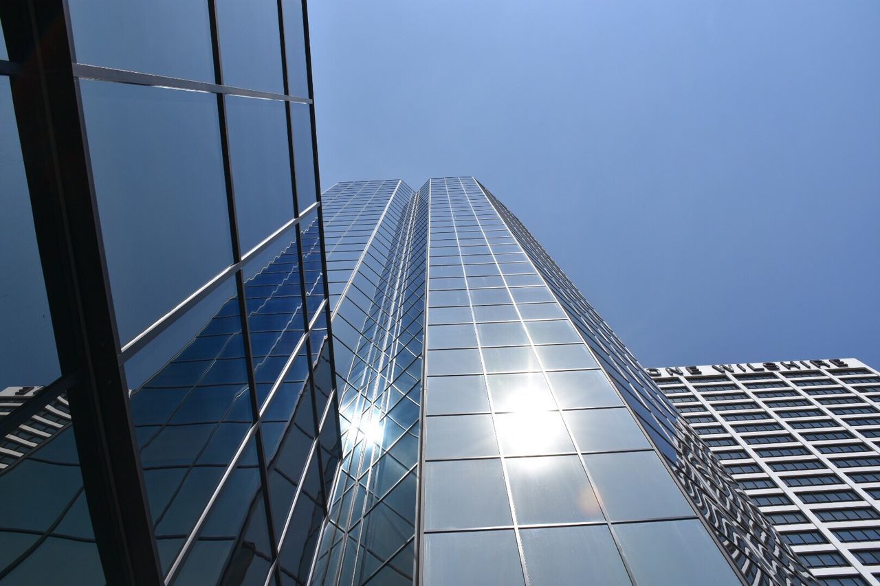 low angle view, built structure, architecture, clear sky, connection, tall - high, modern, building exterior, blue, skyscraper, engineering, diminishing perspective, sky, tower, city, suspension bridge, day, office building, tall, outdoors
