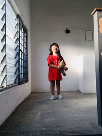 Full length portrait of girl standing against building