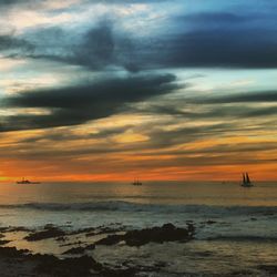 Scenic view of sea against cloudy sky during sunset