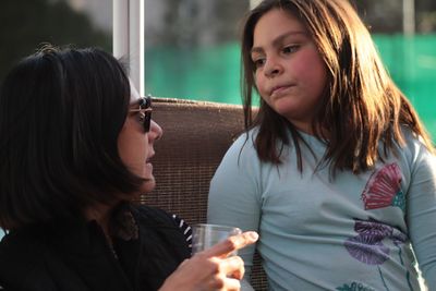 Mature woman with drink looking towards daughter