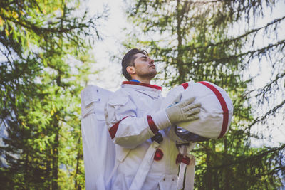 Astronaut looking away while standing in forest